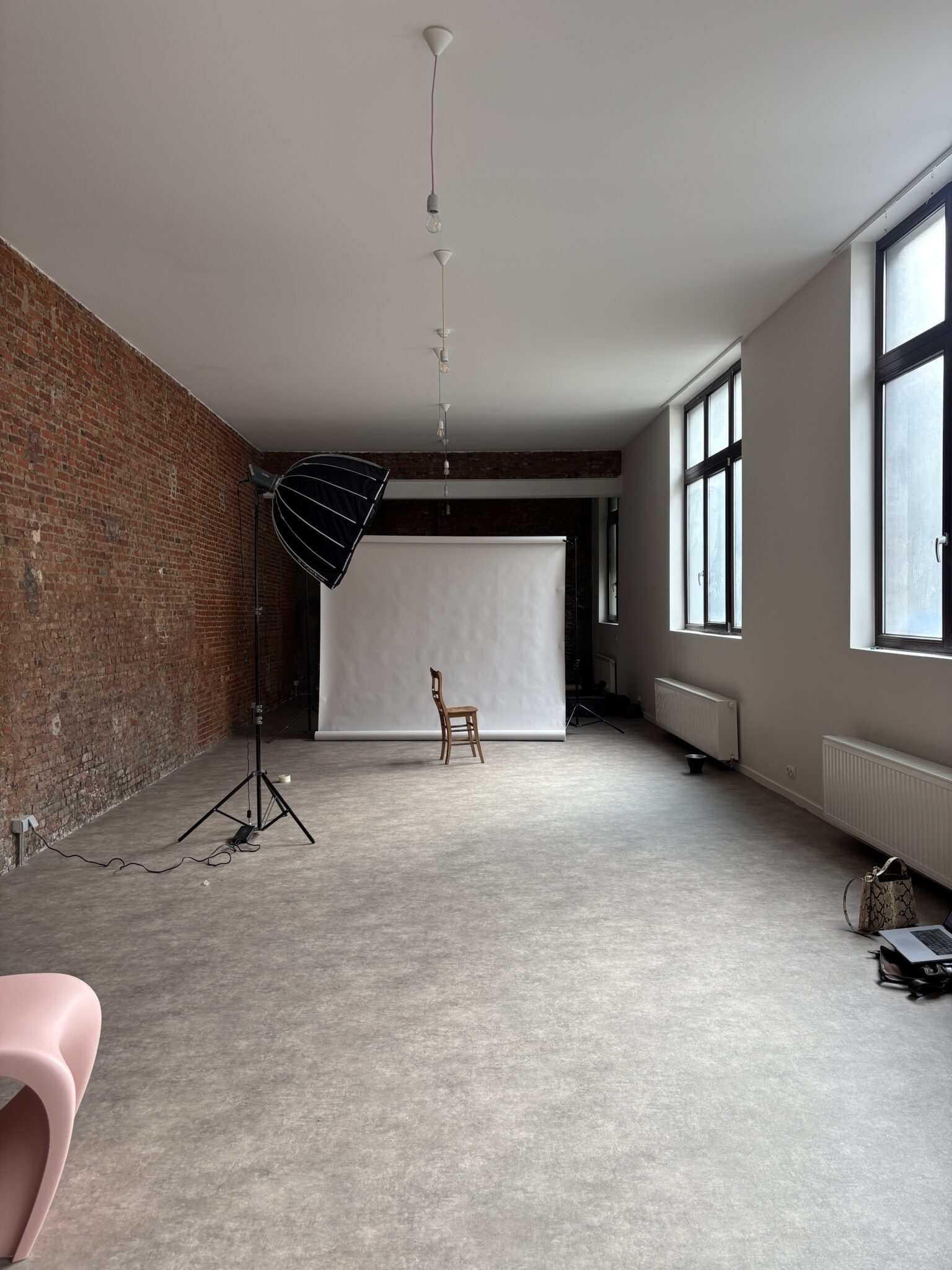 The full 90 m² studio: brick wall, large windows, white paper backdrop and softbox