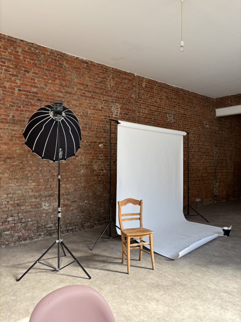 Softbox, wooden chair and white backdrop against the brick wall